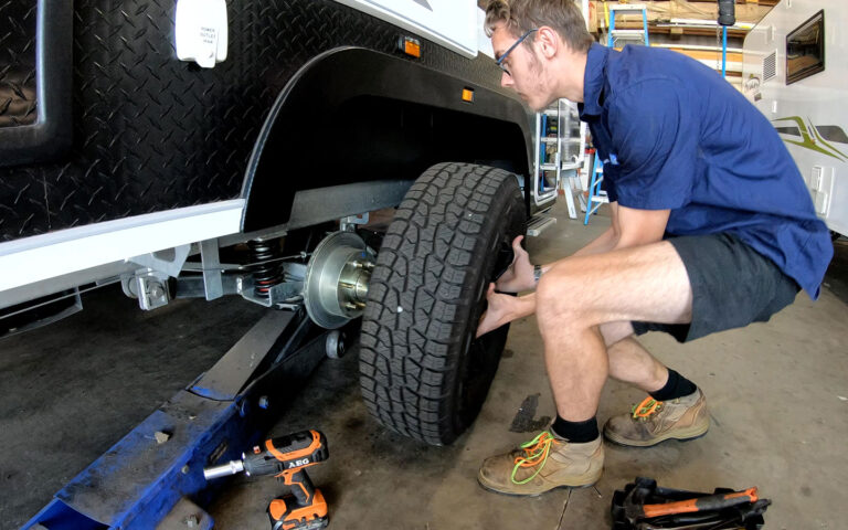 Searle’s RV Centre workshop technician checking the wheel hub and brakes on a caravan in Bundaberg