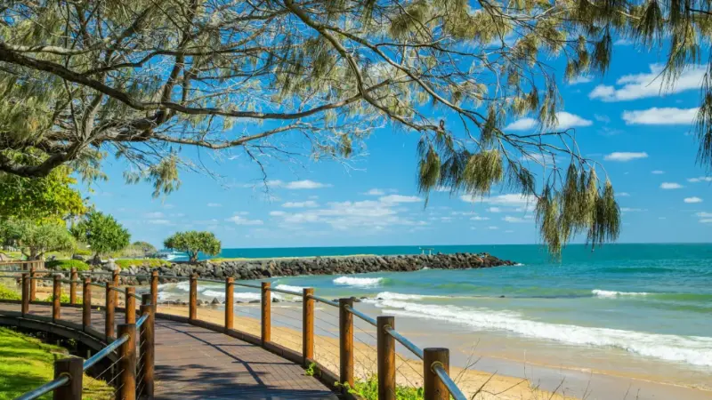 Timber boardwalk along the beachfront at Bargara with the ocean and a rock wall beyond